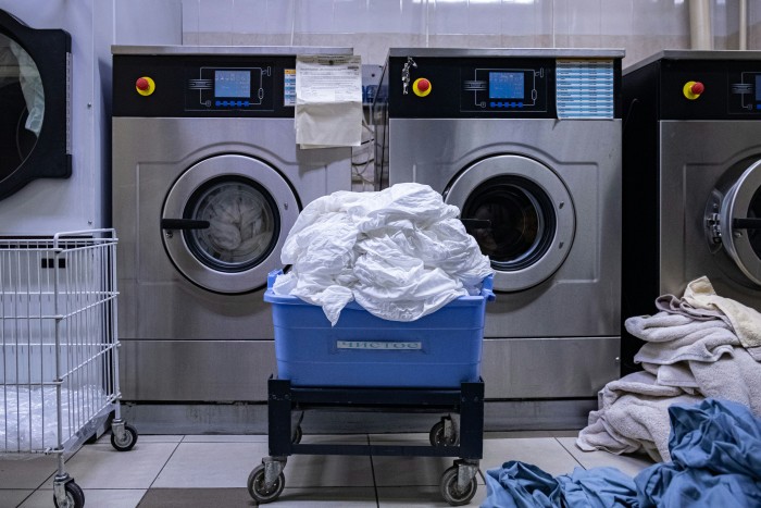 Commercial laundry facility with industrial washing machines cleaning white linens and towels for professional dry cleaning services.